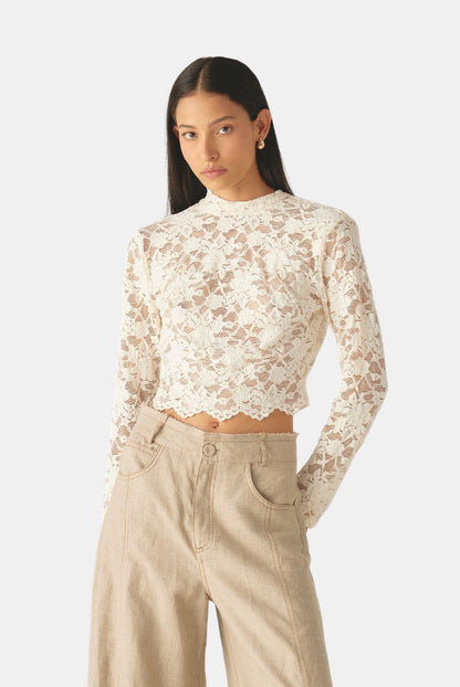 Blusa de encaje floral con cuello alto, mangas largas y silueta ajustada de Mariangélica Guerra.